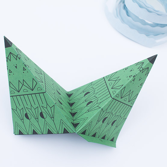 Gluing the tips of a green paper polygon piece for an XXL Christmas star craft.