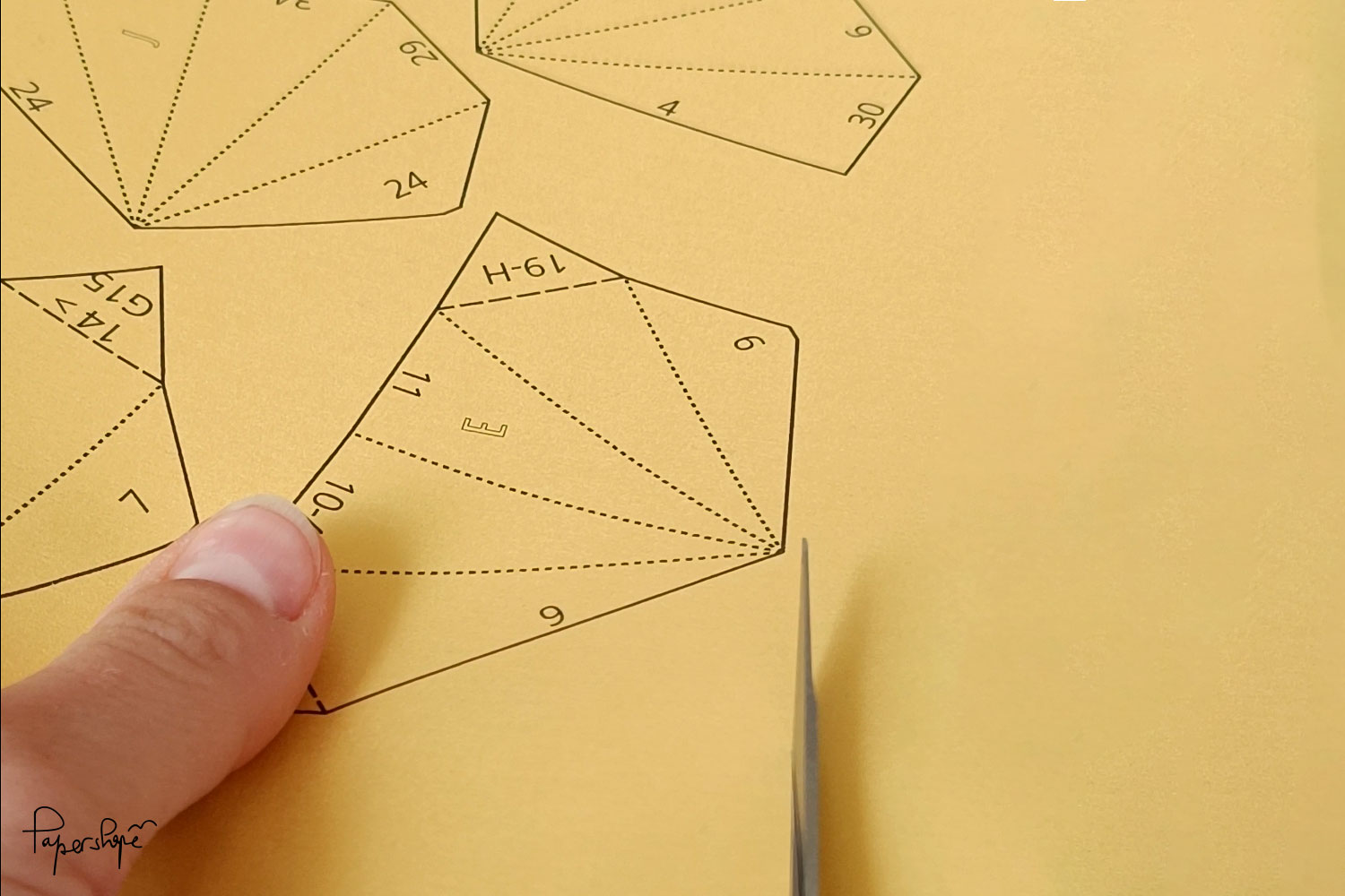 Cutting out the parts of the gold paper Christmas star with scissors