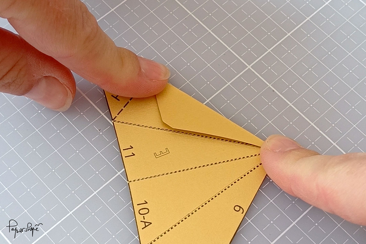 Folding a paper part of the Christmas star along the pre-drawn lines
